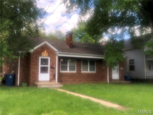 rear view of house featuring brick siding, a chimney, and a lawn
