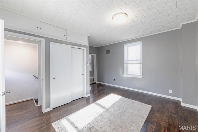 7122 Drury Ln, Saint Louis, MO 63143 - unfurnished bedroom featuring dark wood-style flooring, a closet, ornamental molding, and baseboards