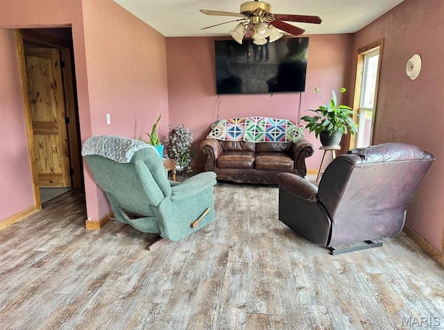 living area with wood finished floors, ceiling fan, and baseboards