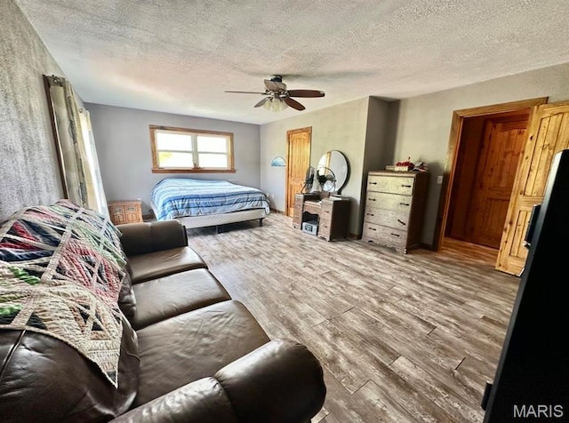 bedroom featuring wood finished floors, a textured ceiling, and a ceiling fan