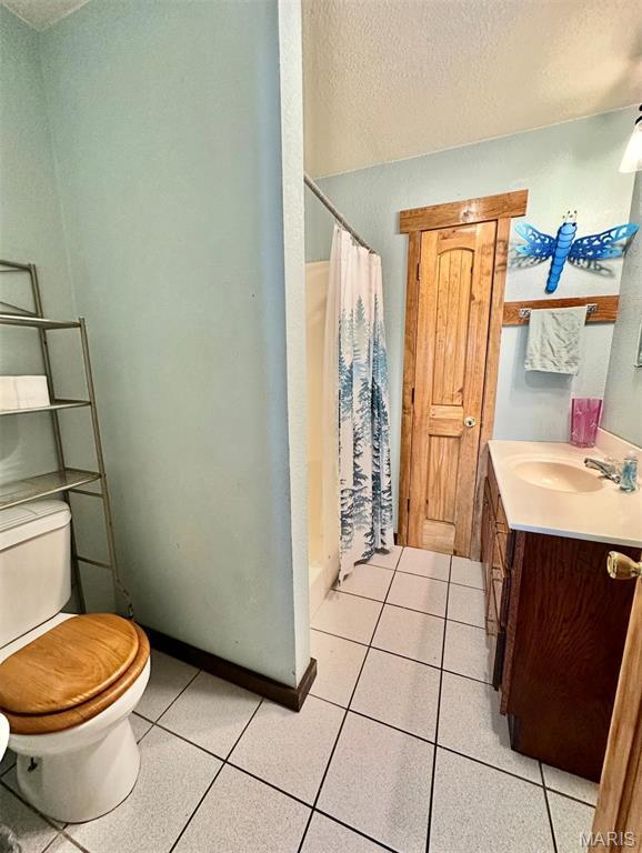 bathroom featuring toilet, a textured ceiling, vanity, a shower with curtain, and tile patterned floors