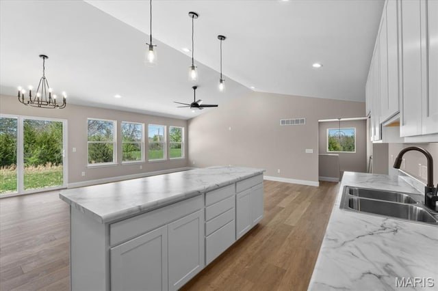 1423 Wild Ridge Estates Ct, Florissant, MO 63033 - kitchen with a sink, vaulted ceiling, baseboards, open floor plan, and light wood-type flooring