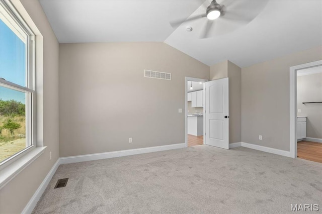 1423 Wild Ridge Estates Ct, Florissant, MO 63033 - unfurnished bedroom with light carpet, vaulted ceiling, multiple windows, baseboards, and ensuite bath