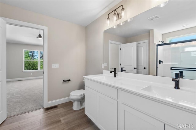 1423 Wild Ridge Estates Ct, Florissant, MO 63033 - full bathroom featuring wood finished floors, baseboards, toilet, double vanity, and a ceiling fan