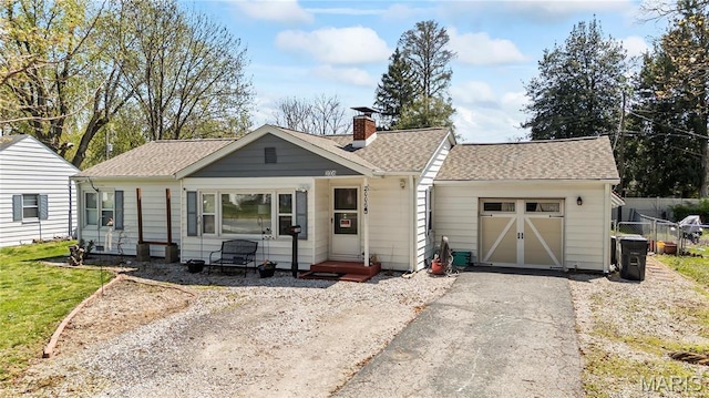 ranch-style home featuring an attached garage, driveway, a chimney, and roof with shingles