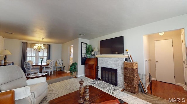 living room featuring a chandelier, wood finished floors, baseboards, and a fireplace with flush hearth