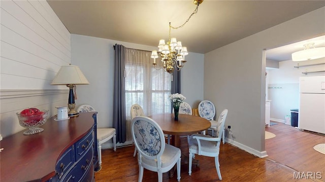 dining space featuring a chandelier, dark wood finished floors, and wood walls