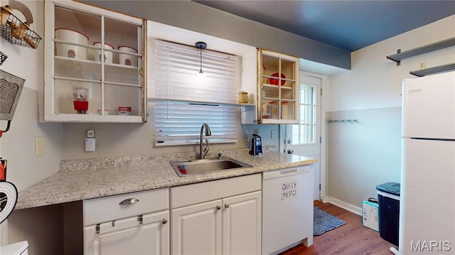 kitchen with white appliances, a sink, wood finished floors, white cabinetry, and light countertops