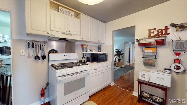 kitchen with under cabinet range hood, white gas stove, black microwave, wood finished floors, and white cabinetry