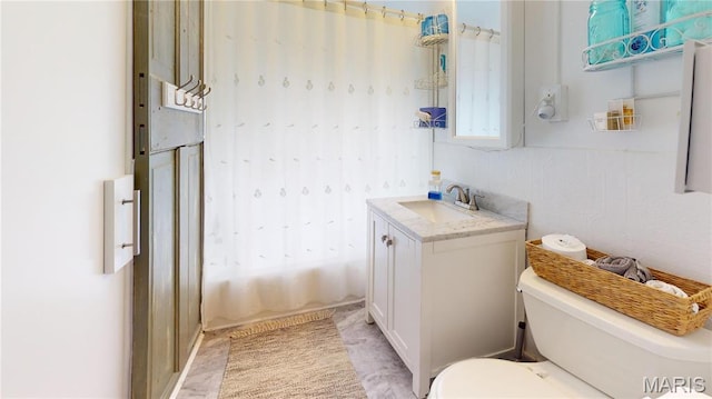 bathroom featuring toilet, shower / bath combo with shower curtain, and vanity