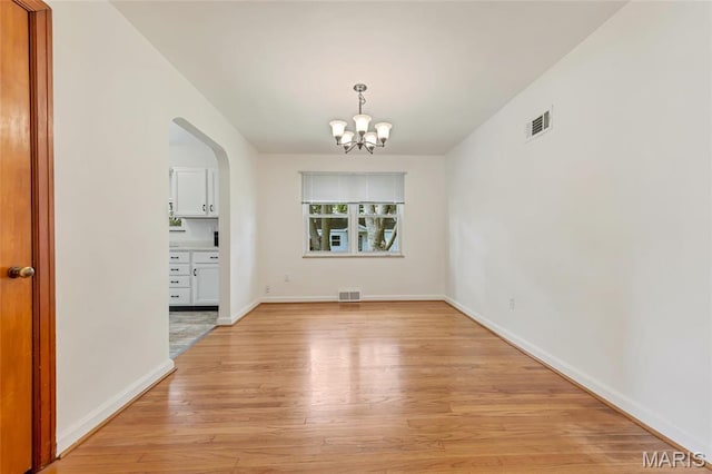 509 N Jefferson St, Mascoutah, IL 62258 - unfurnished dining area with a chandelier, arched walkways, light wood-style floors, and baseboards