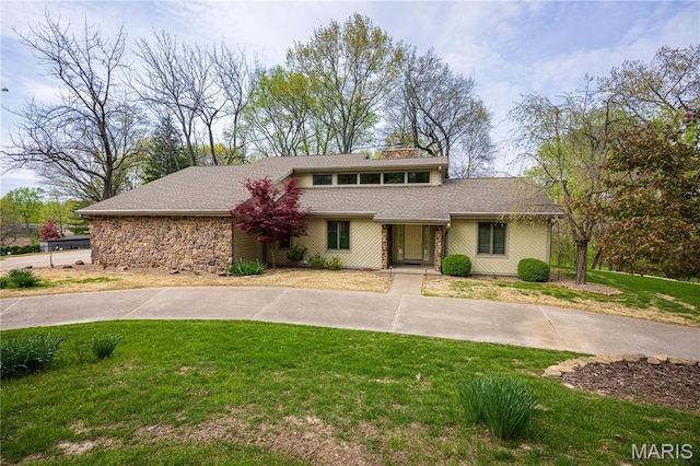 mid-century home with a front yard and stone siding