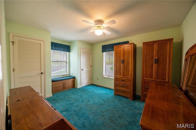 carpeted bedroom with baseboards, multiple closets, a textured ceiling, and a ceiling fan