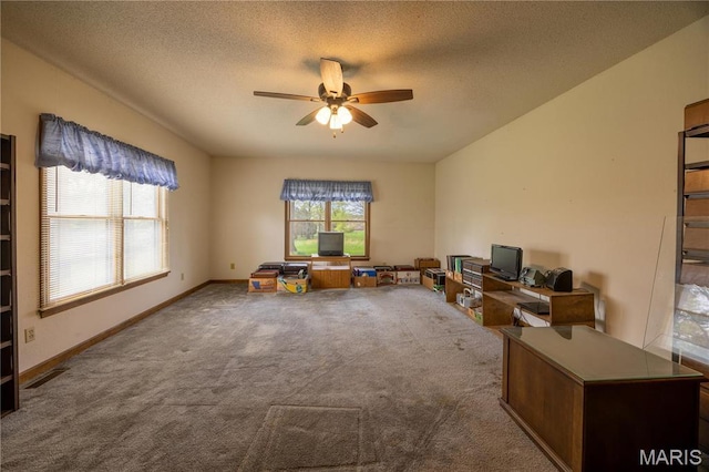 carpeted office space with ceiling fan, a textured ceiling, and baseboards