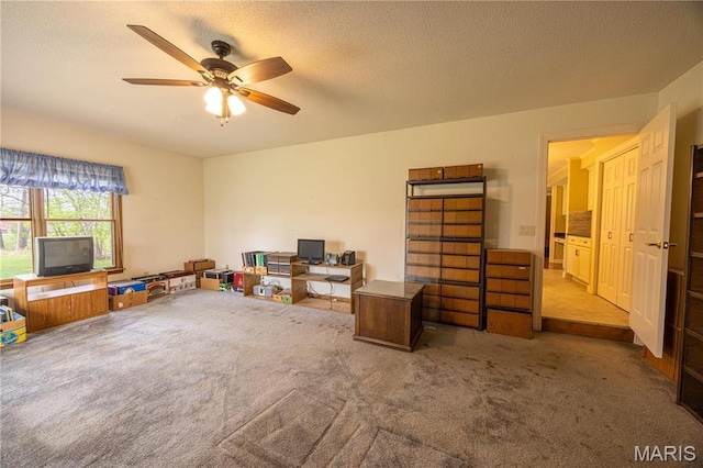rec room featuring carpet, ceiling fan, and a textured ceiling