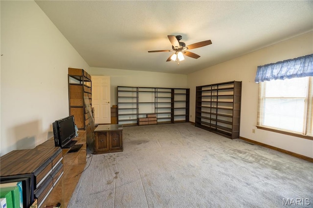 interior space with carpet flooring, a ceiling fan, and baseboards