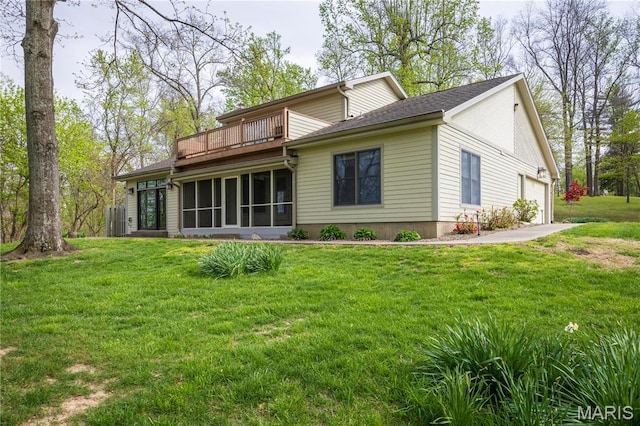 rear view of property with an attached garage, a balcony, a yard, and a sunroom