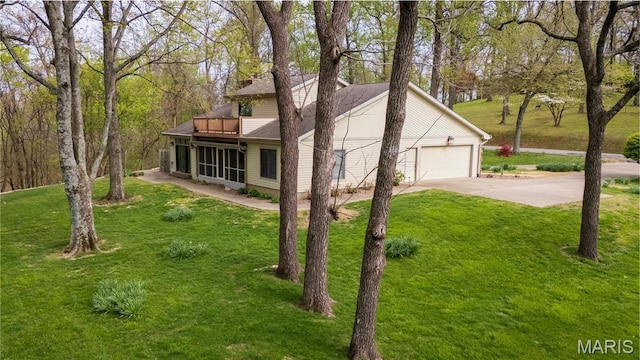 view of side of home with a garage, driveway, a yard, and a balcony
