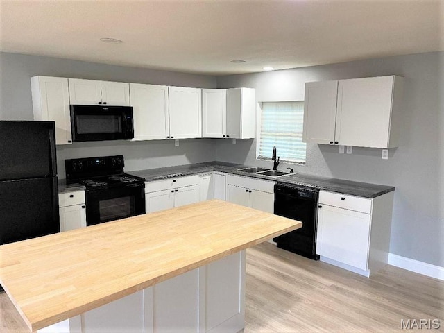 kitchen with black appliances, a sink, butcher block counters, white cabinets, and recessed lighting