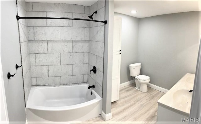 bathroom with baseboards, washtub / shower combination, toilet, wood finished floors, and vanity