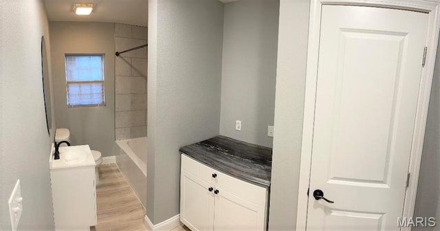 bathroom with wood finished floors, toilet, vanity, and shower / bath combination