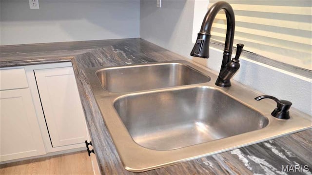 kitchen view of a sink, white cabinetry, and dark countertops