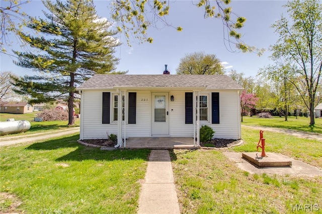 view of front of property with covered porch, a front lawn, and a chimney