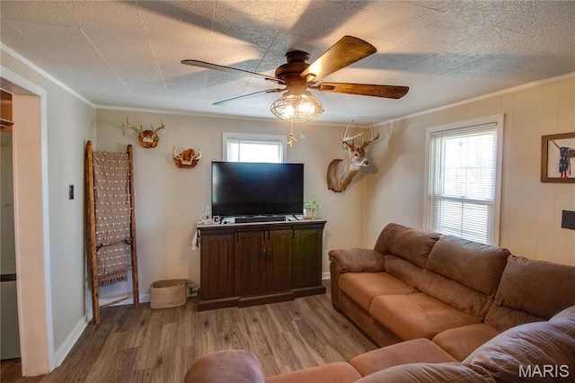living room featuring wood finished floors, ornamental molding, and a ceiling fan