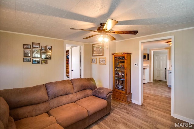 living room featuring a ceiling fan, light wood-style flooring, crown molding, and baseboards