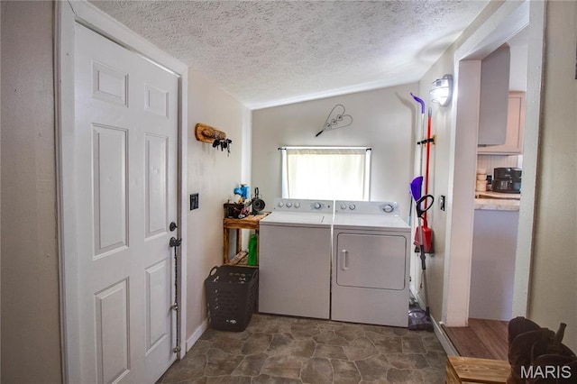 laundry area featuring a textured ceiling, washer and clothes dryer, and dark stone finish floors