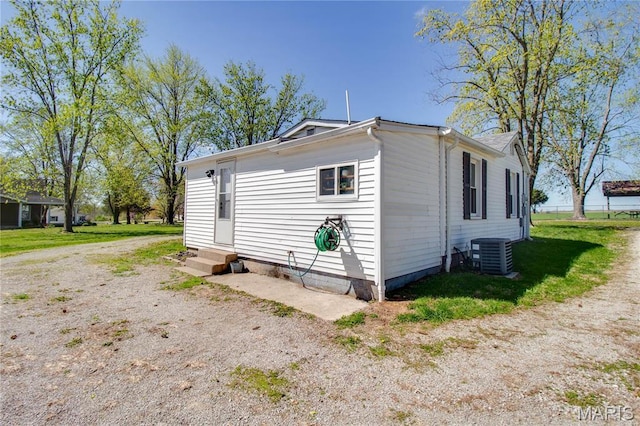 view of home's exterior featuring entry steps, central AC unit, and a lawn