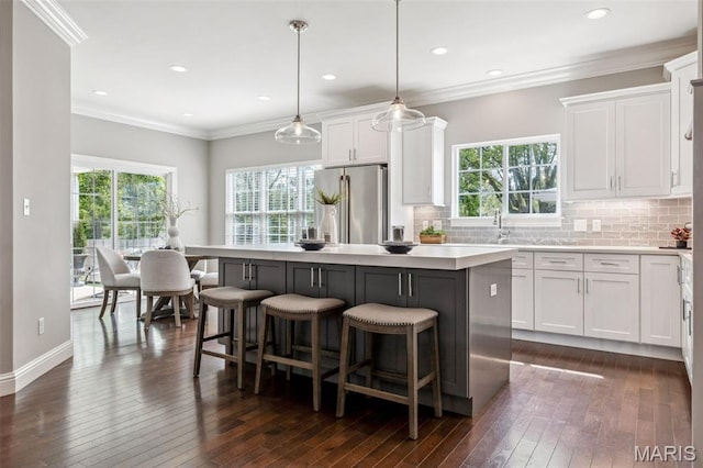 11910 Lillian Ave, Saint Louis, MO 63131 - kitchen with freestanding refrigerator, dark wood finished floors, white cabinets, decorative backsplash, and a breakfast bar