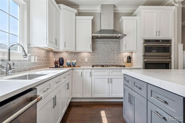 11910 Lillian Ave, Saint Louis, MO 63131 - kitchen with wall chimney range hood, stainless steel appliances, a sink, light countertops, and white cabinets