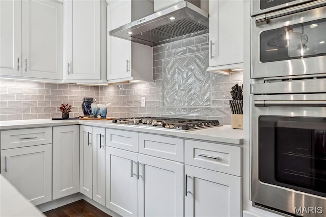 11910 Lillian Ave, Saint Louis, MO 63131 - kitchen with wall chimney range hood, stainless steel appliances, light countertops, and white cabinetry