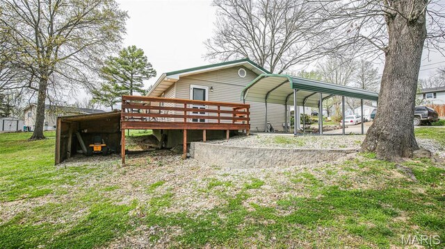 14153 Spring Dr, De Soto, MO 63020 - back of house featuring a detached carport, a deck, driveway, and a lawn