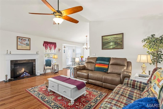 living room with vaulted ceiling, ceiling fan, wood finished floors, a chandelier, and a premium fireplace