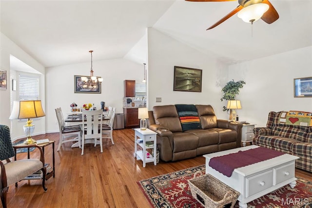 living area featuring a chandelier, light wood-style flooring, vaulted ceiling, and a ceiling fan