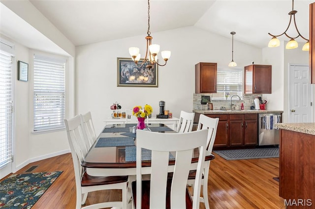 dining area featuring a chandelier, wood finished floors, vaulted ceiling, and plenty of natural light