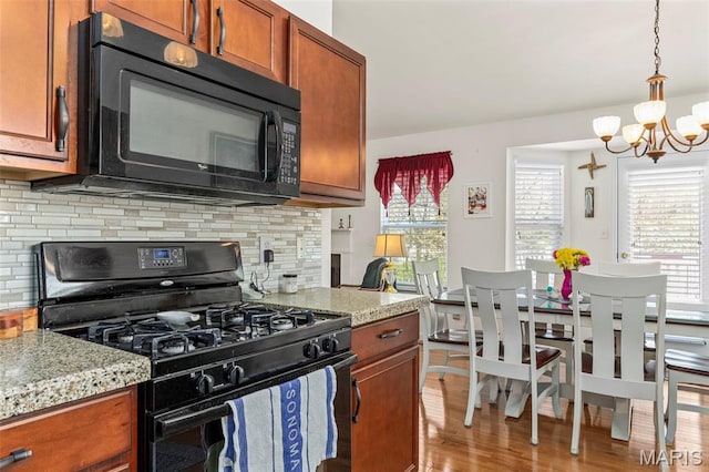 kitchen featuring black appliances, a chandelier, backsplash, decorative light fixtures, and wood finished floors
