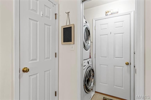 laundry area featuring stacked washer and clothes dryer and light tile patterned flooring