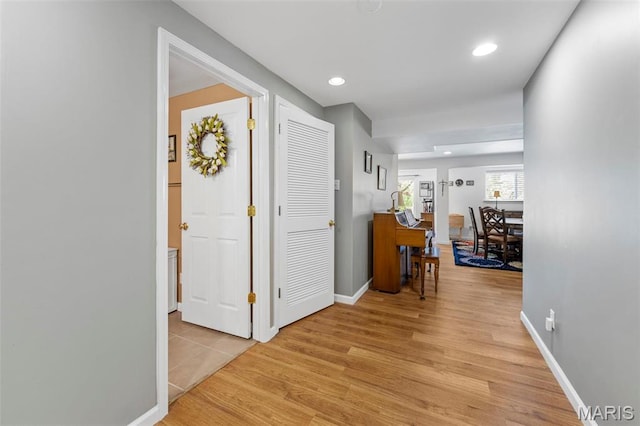 corridor with light wood-style floors, baseboards, and recessed lighting
