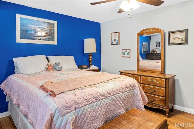 bedroom with wood finished floors, baseboards, and a ceiling fan