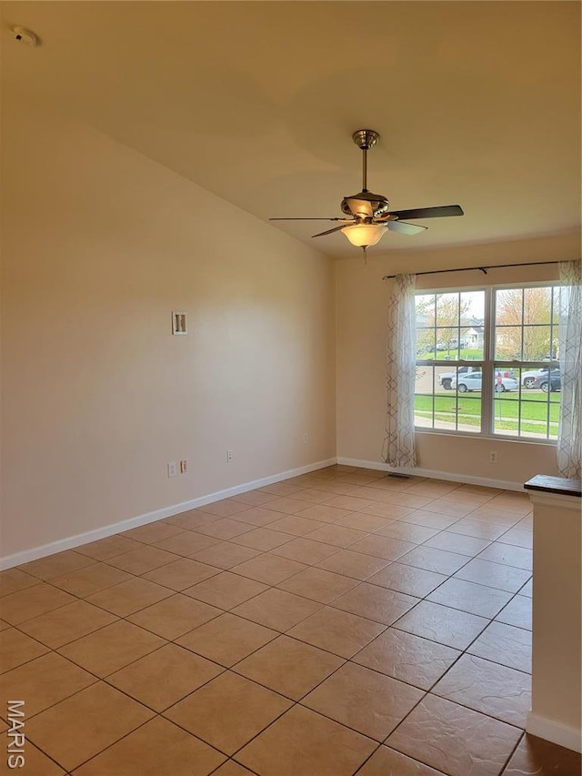 empty room with baseboards, a ceiling fan, and light tile patterned floors