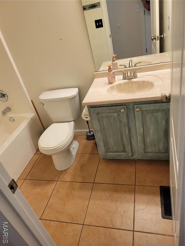 bathroom featuring tile patterned flooring, toilet, vanity, a tub, and baseboards