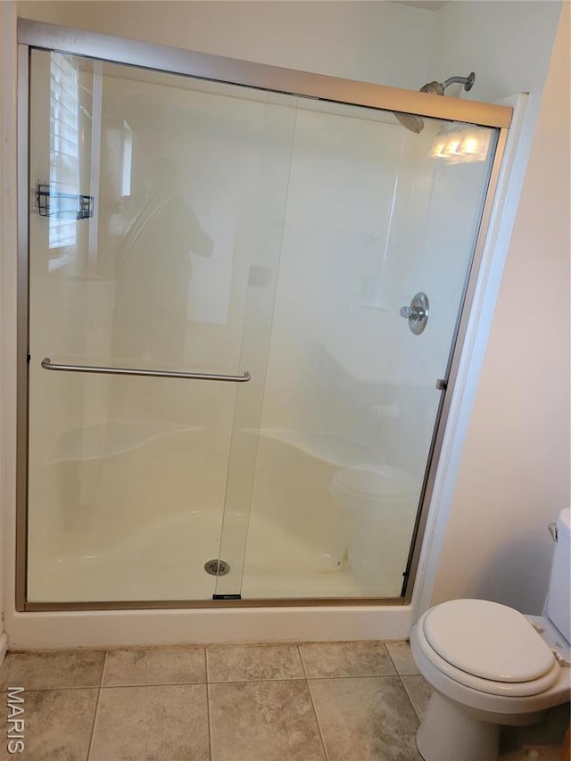 full bathroom with a shower stall, toilet, and tile patterned floors