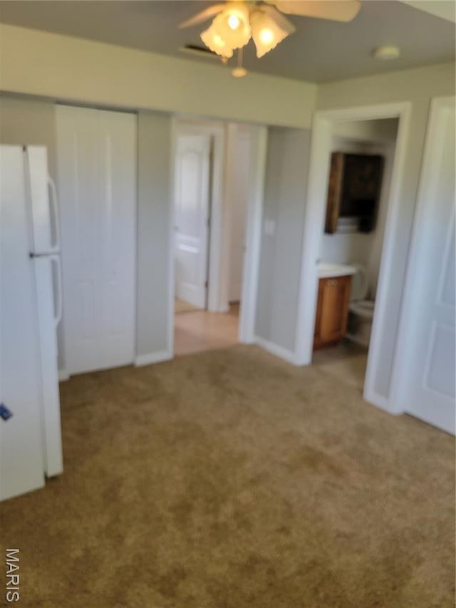 unfurnished bedroom featuring freestanding refrigerator, carpet floors, and ensuite bath