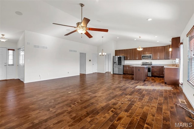 kitchen featuring appliances with stainless steel finishes, open floor plan, vaulted ceiling, a center island, and a chandelier