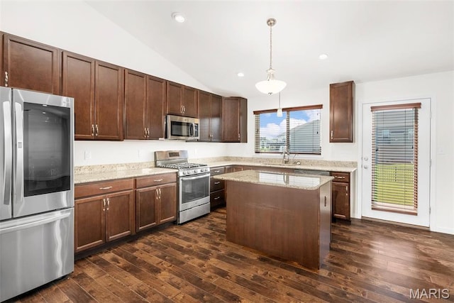 kitchen with appliances with stainless steel finishes, a sink, lofted ceiling, dark wood finished floors, and decorative light fixtures