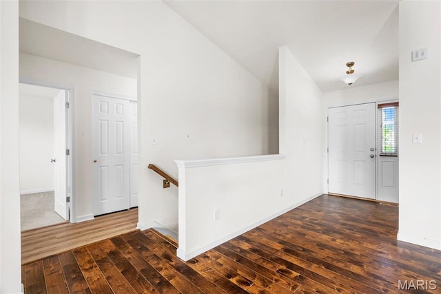 foyer entrance featuring dark wood-style flooring, baseboards, and vaulted ceiling