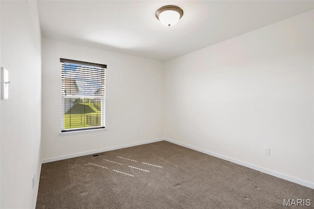 spare room featuring carpet and baseboards